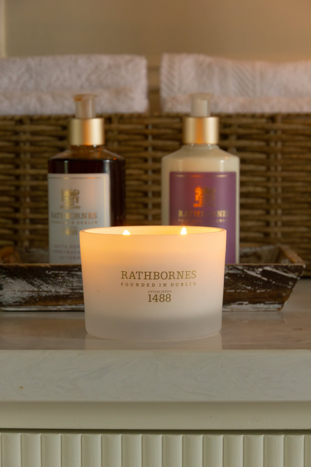 Candle with Bath and Body Wash & Lotion on a bathroom marble platform.