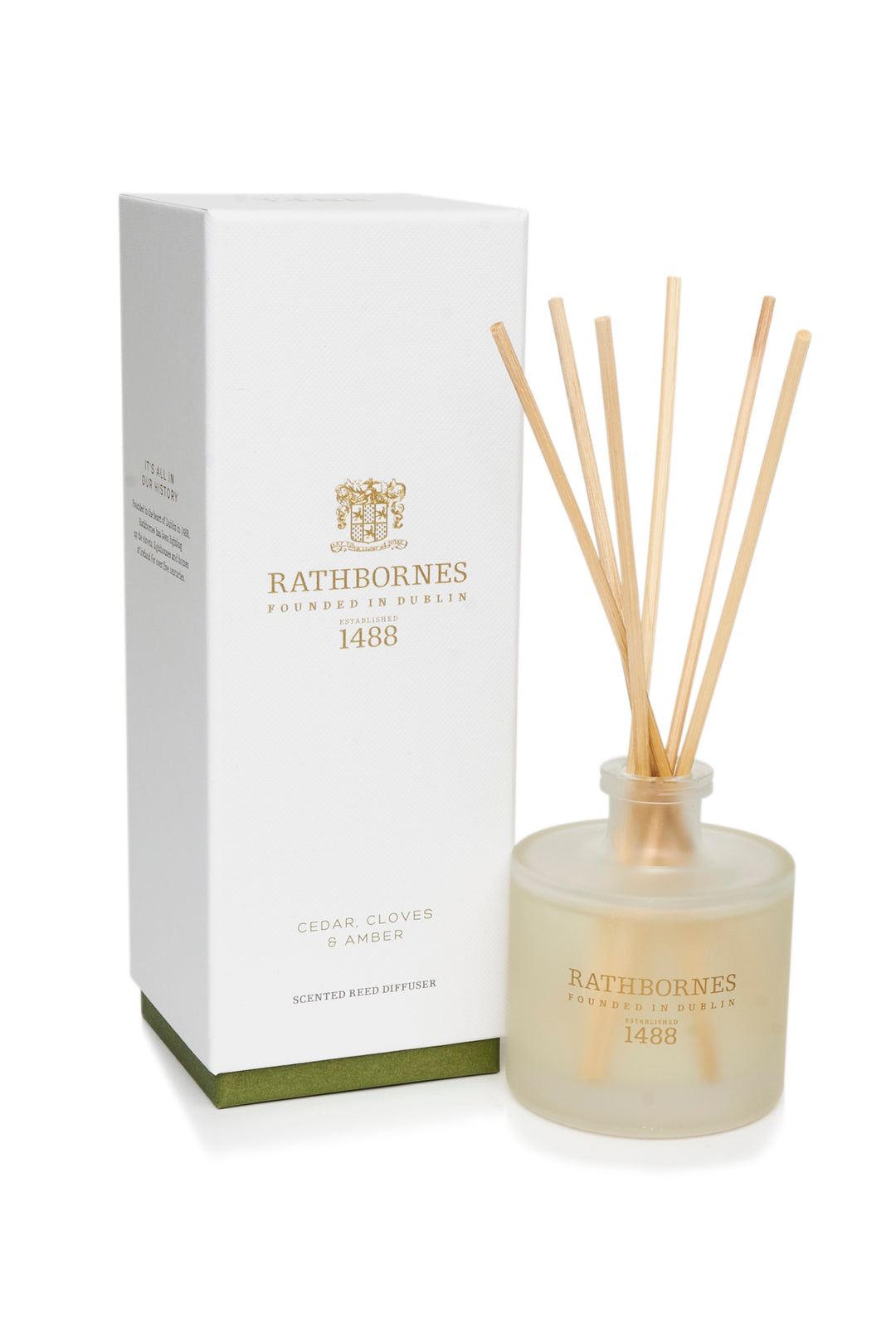 A white reed diffuser with cedar, cloves, and amber scent, alongside its packaging box.