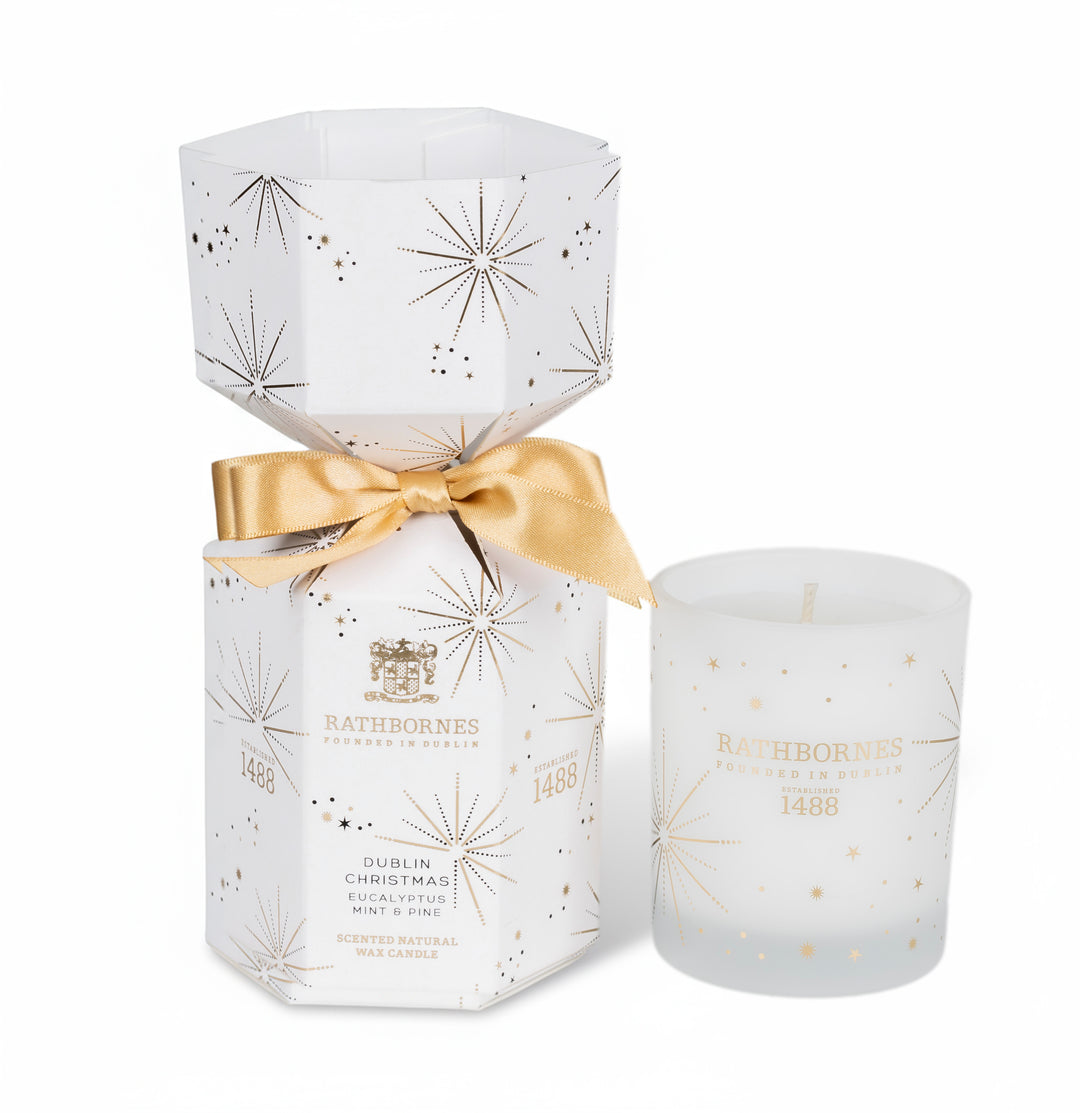 White candle with gold accents and 'Rathborne' branding on a white background