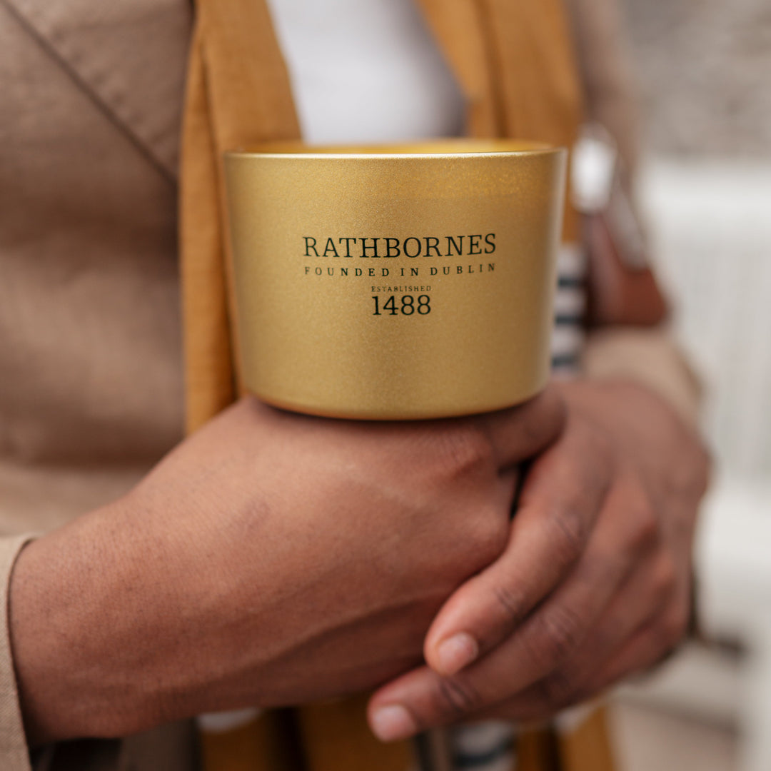 Gold candle  with 'Rathbornes' branding held by a person