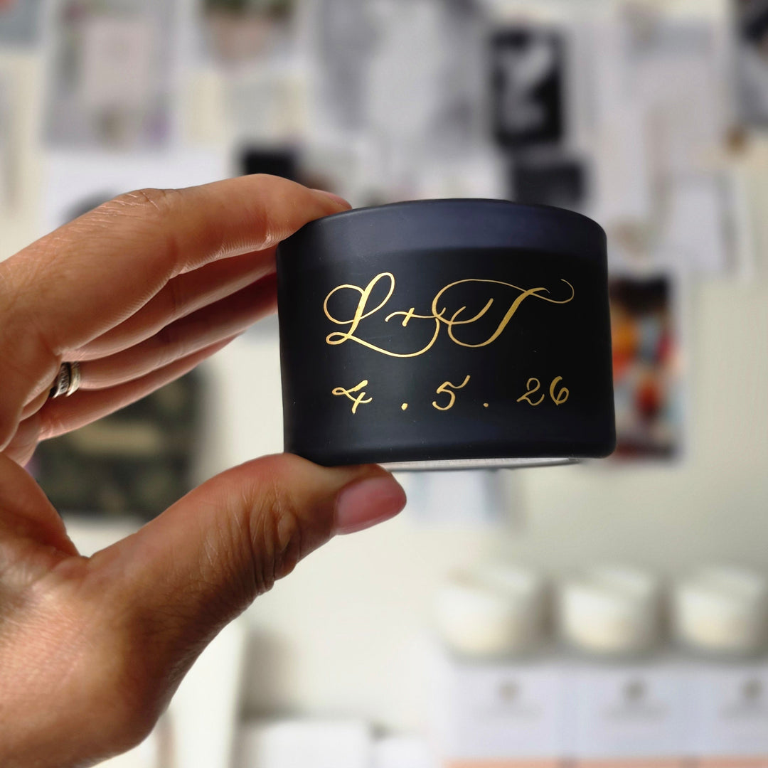 A woman holding a small black candle with calligraphy on it.