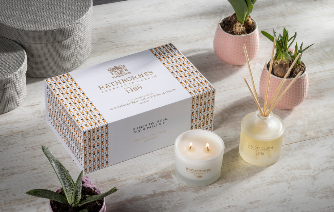 Rathborne's candles and diffuser on a wooden surface with plants