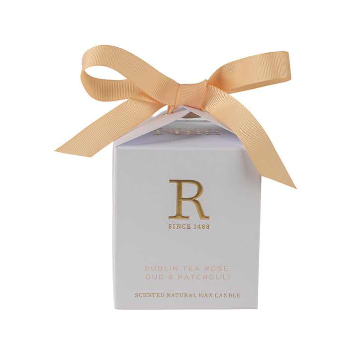 Candle packaging with a gold bow on a white background