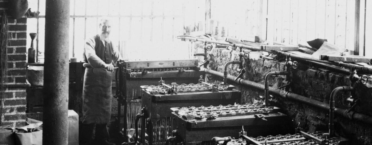 Vintage photo of the Rathbornes factory with large mechanical machines and a person in an apron.