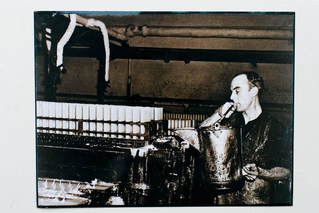 Black and white photograph of a person operating machinery in a candle factory.