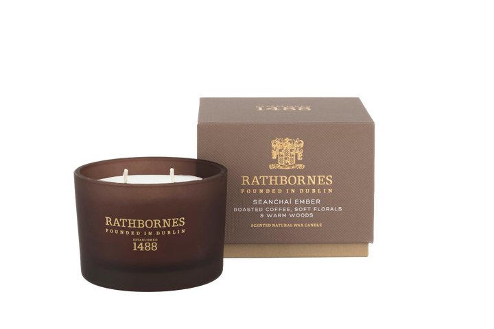 Brown candle with 'Rathbornes' branding next to its packaging with no background