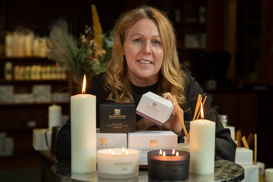 Woman holding a scented candle box with pillar candles on the table.