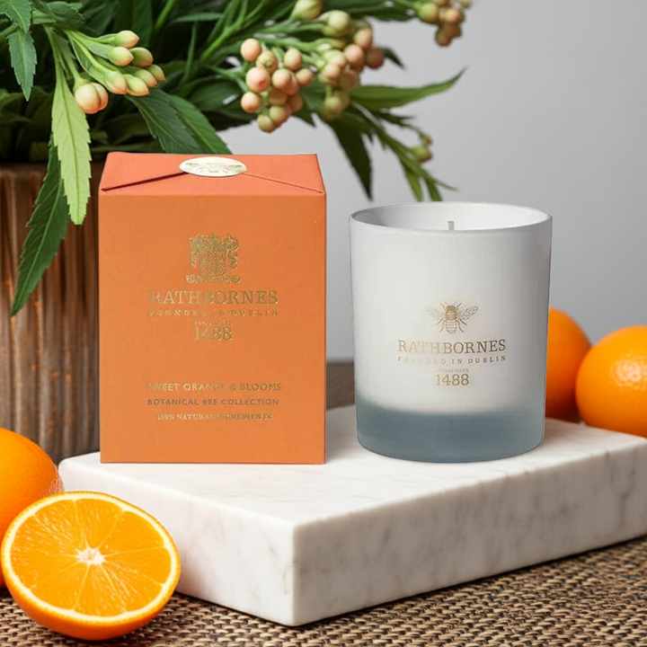 Candle and packaging with oranges and a plant on a marble surface