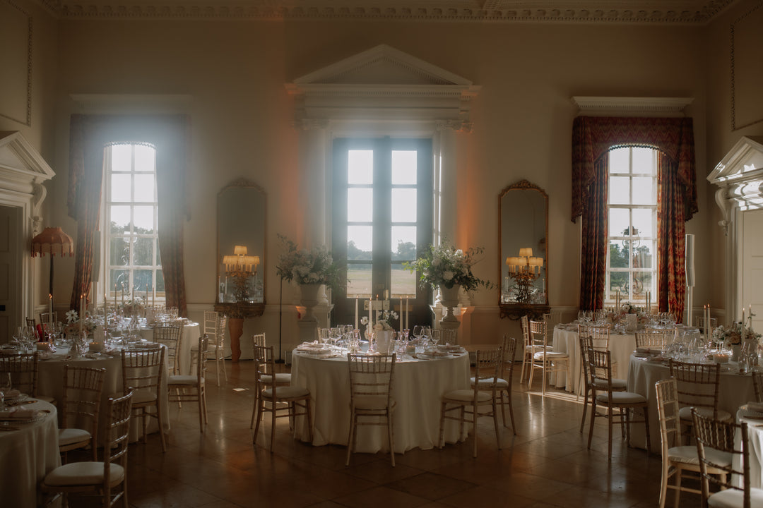 Grand room with tables set for a formal event, large windows allowing natural light.