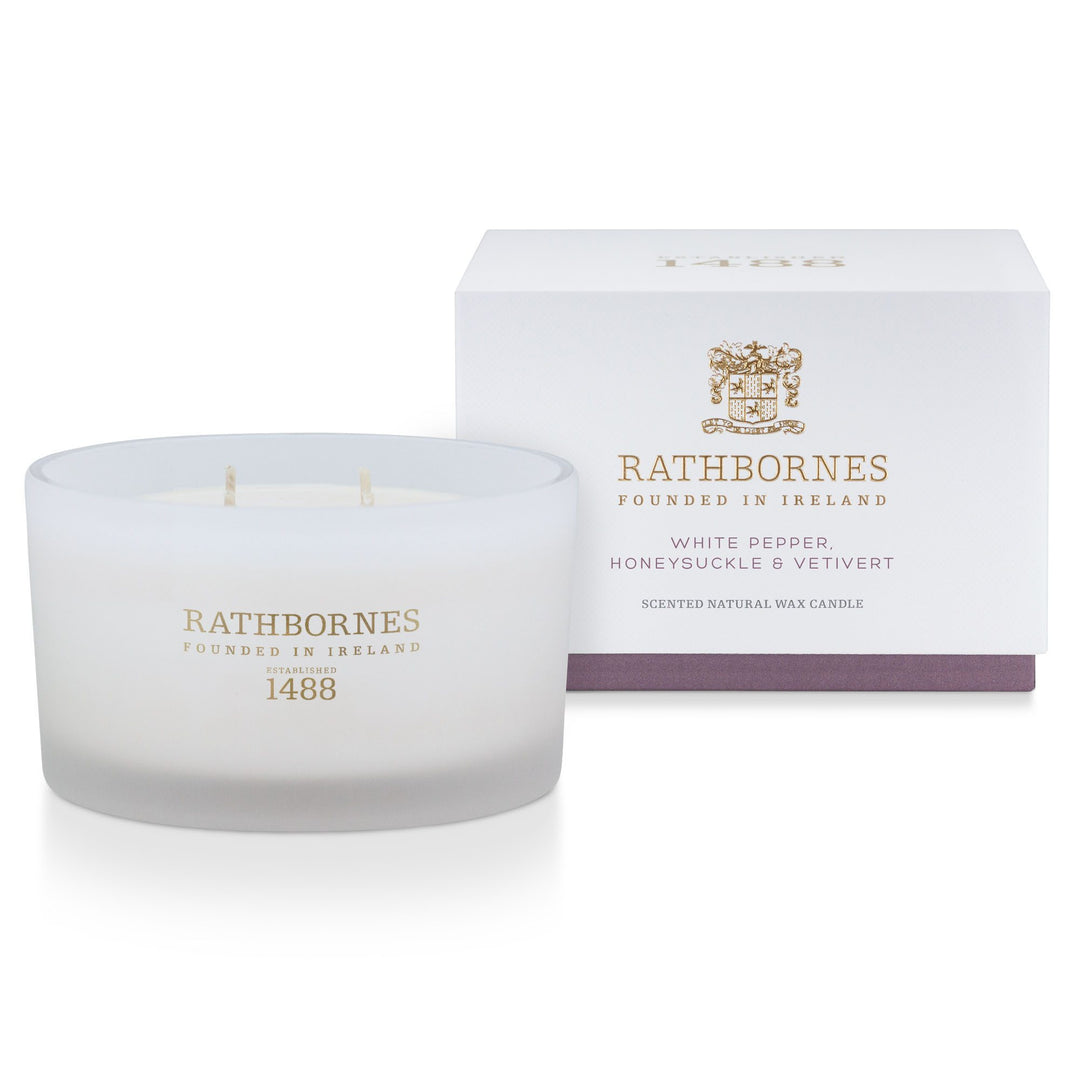 Rathbornes White Pepper, Honeysuckle & Vetivert luxury scented candle beside its white gift box with mauve base