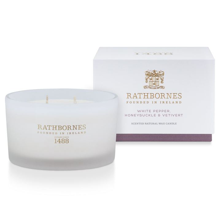Rathbornes White Pepper, Honeysuckle & Vetivert luxury scented candle beside its white gift box with mauve base