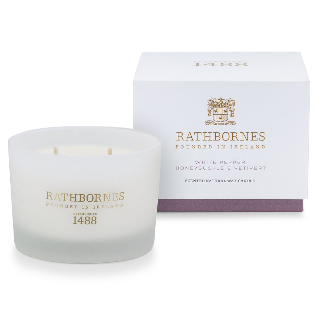 Rathbornes White Pepper, Honeysuckle & Vetivert classic scented candle beside its white gift box with mauve base