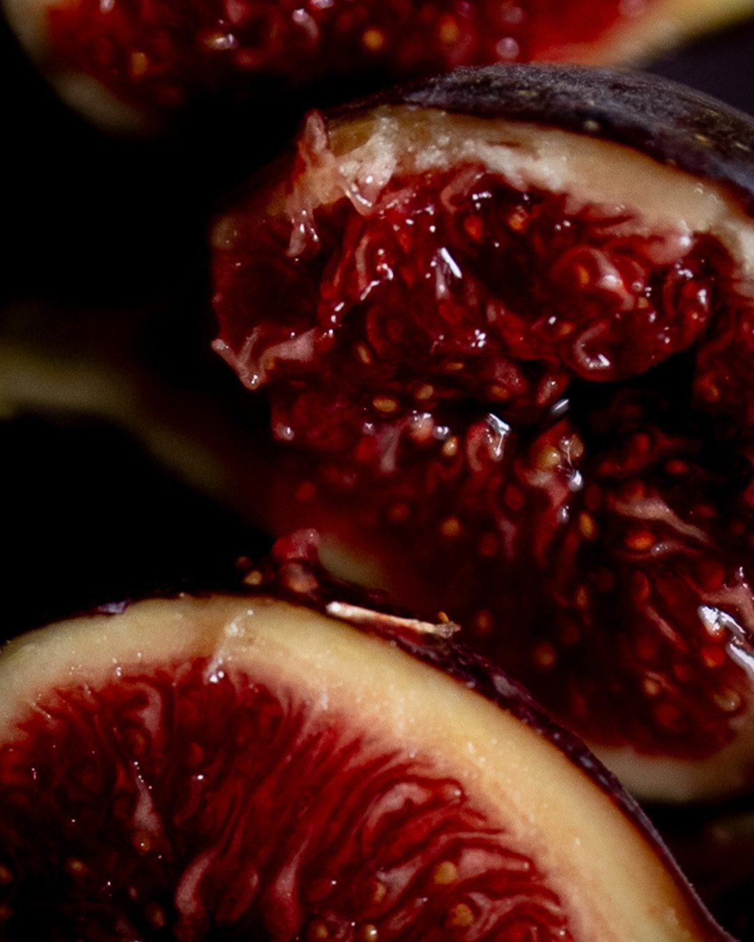 Halved ripe purple figs with glistening red flesh, the top notes of the Rathbornes Seanchaí Dún candle