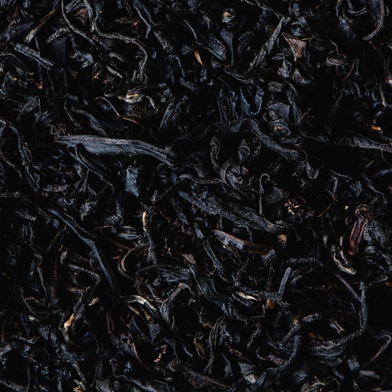 Close-up of dark smoked loose leaf tea, a heart note of the Rathbornes Seanchaí Dún candle